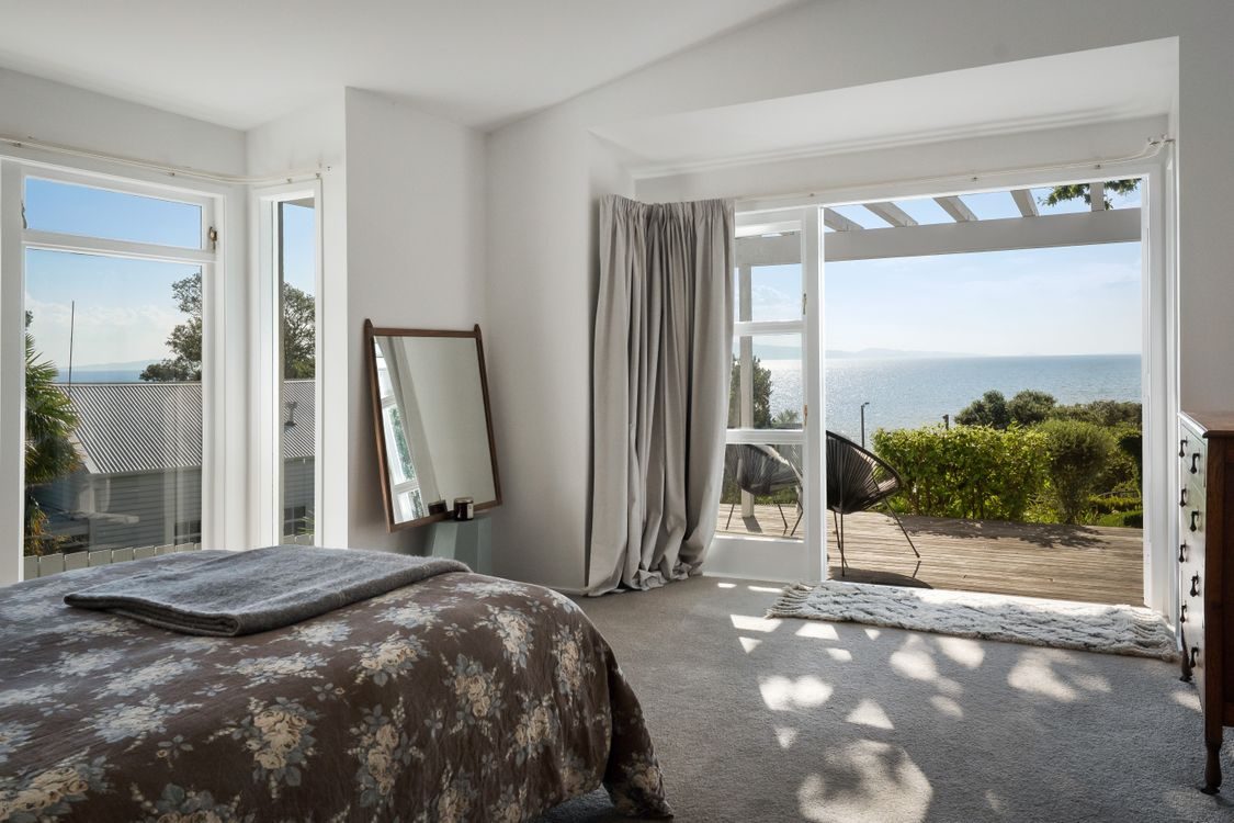 A sunlit bedroom opening to the deck and sea